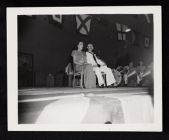 USS Saratoga birthday party, woman and man sitting on a stage 